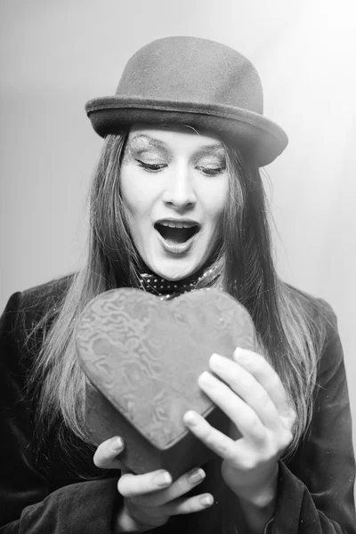 Portrait of elegant beautiful young lady joyfully opening present box in the form of heart