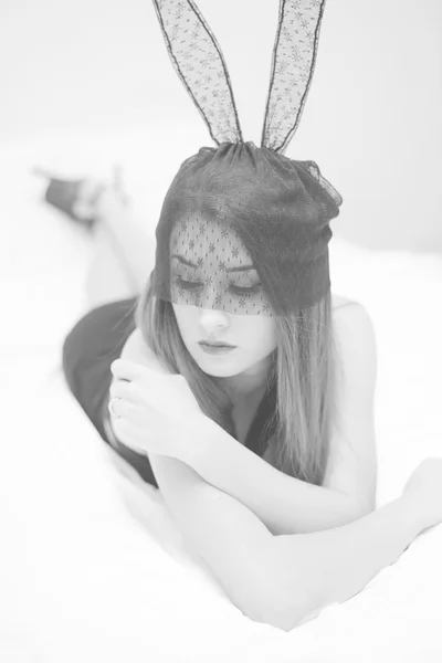 Sexy mysterious beautiful lady and bunny ears mask relaxing in bed. Black and white picture