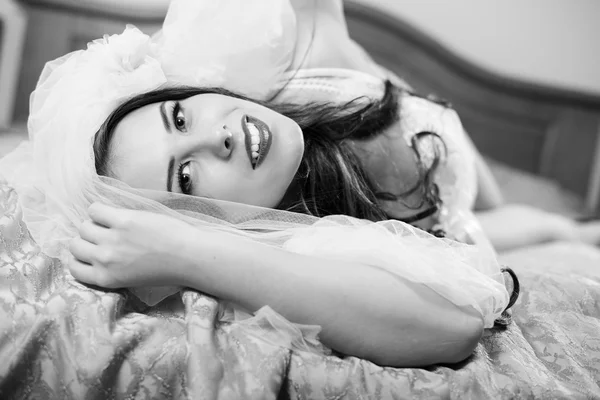 Beautiful sensual young lady in white lingerie relaxing in bed. Black and white photography