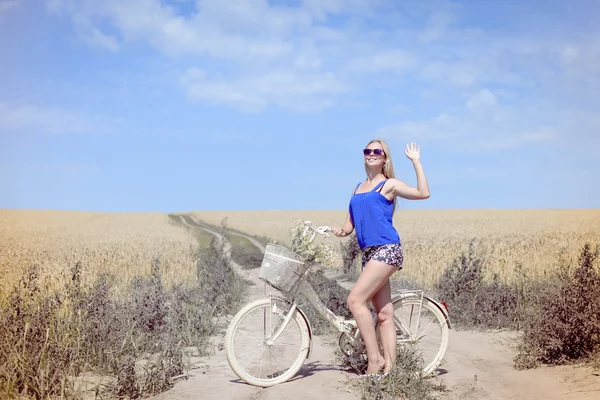 Pretty woman with bike on countryside landscape blue sky background outdoors