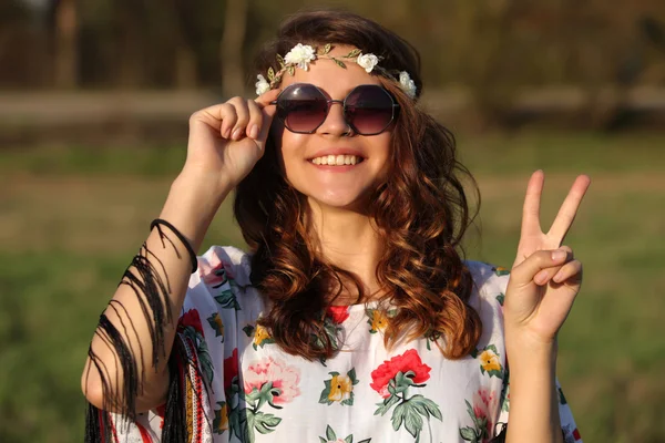 Happy young girl hippie smiles and showing sign of peace Outdoors