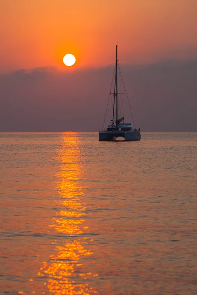 Sailing catamaran on the background of the rising sun on the sea