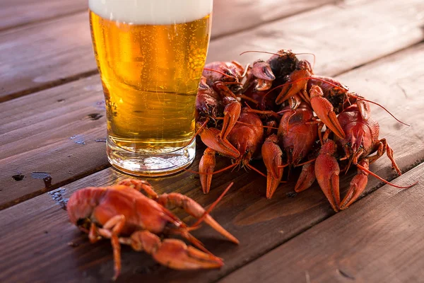 Full glass of beer with boiled crawfish on the table