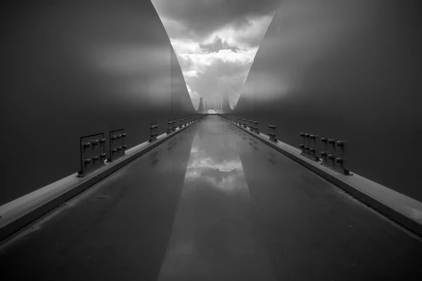 Contemporary black and white architecture object with rounded lines and dramatic cloudy sky. Reflection of clouds on steel construction that looks like spaceship board.