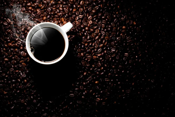 Steaming coffee cup with a coffee beans background