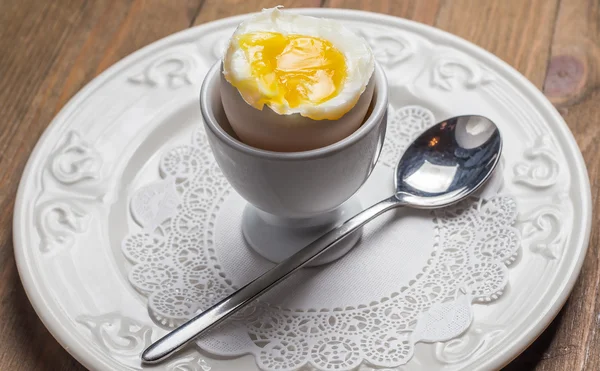 Breakfast with soft-boiled egg, over old wooden table.