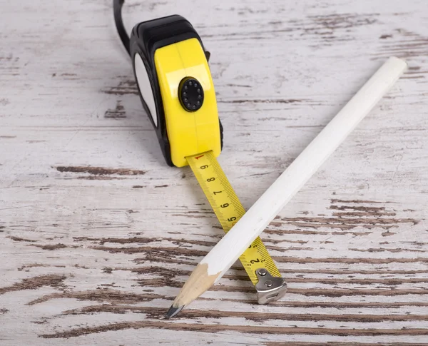 Tape measure and pencil on grunge  wooden background