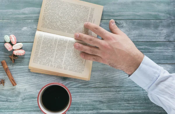 Man reading a book and writing notes on wooden table