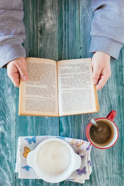 Man reading a book and writing notes on wooden table