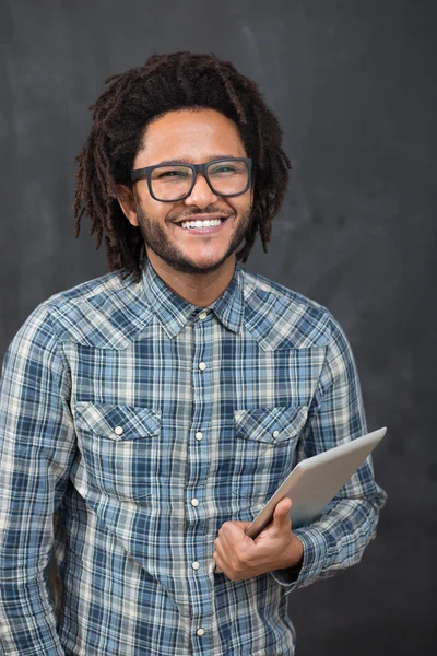 Enjoying his digital tablet. Cheerful young African man holding