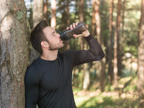 Athletic sport man drinking water from a bottle. Cold drink afte