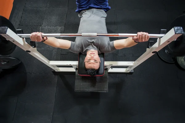 Young Man In Gym Exercising Chest On The Bench Press - top view