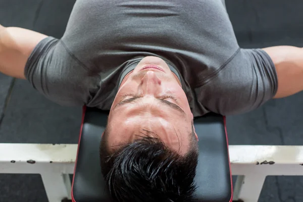 Young Man In Gym Exercising Chest On The Bench Press - top view