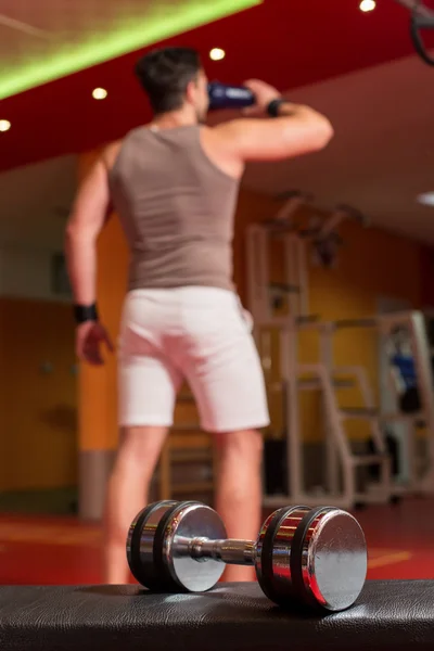 Big dumbbells with active body builder in background