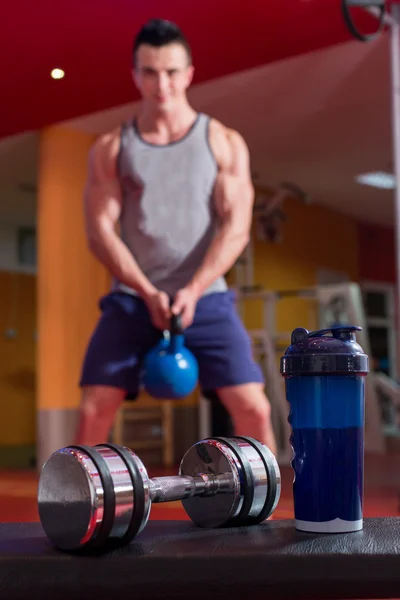 Whey protein shaker and dumbbells. Fitness and bodybuilding man