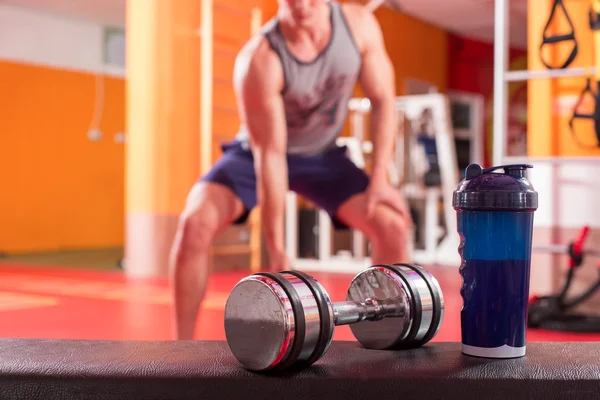 Whey protein shaker and dumbbells. Fitness and bodybuilding man