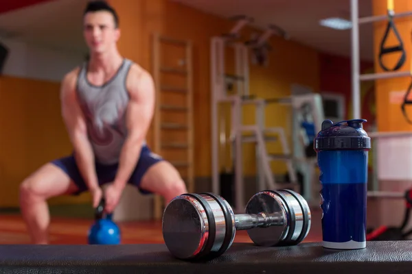 Whey protein shaker and dumbbells. Fitness and bodybuilding man