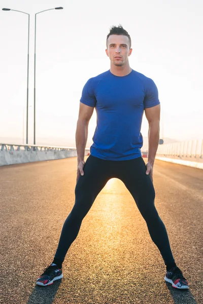 Portrait Of Male Runner On highway sunset, streching legs