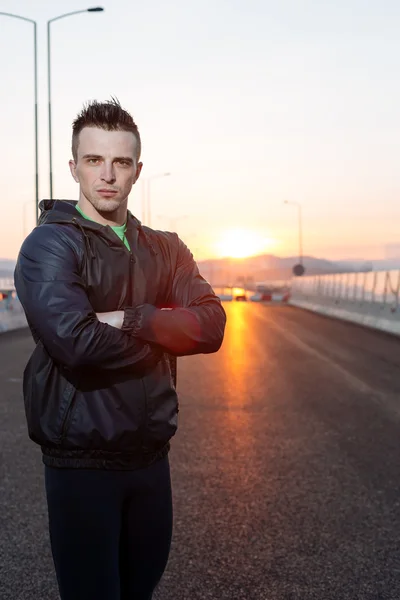 Handsome urban jogger rposing on the bridge