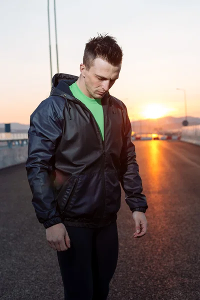 Athletic man relaxing after hard work out, highway sunset