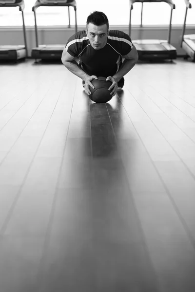 Young Man Exercise With Medical Ball In Fitness Club