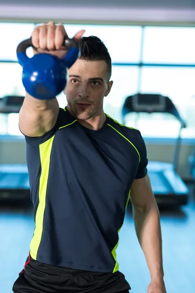Exercise With Kettle Bell. Athletic man doing exercises with blu