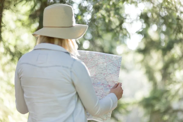 Young feYoung woman sitting with paper map near the car in the f