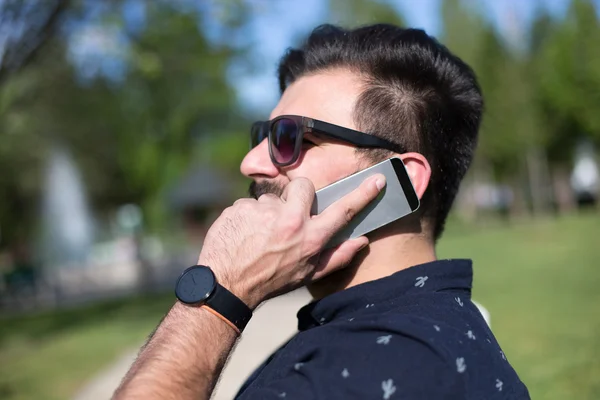 Happy man using a smart phone outdoor with a green background