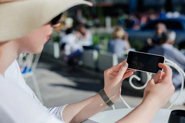 Detail of a beautiful young woman in hat holding a phone in his