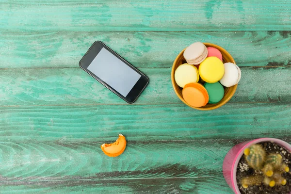 Mobile phone, tablet with coffee cup  and cakes on rustic  woode