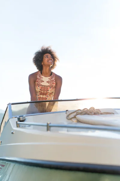 Summer vacation - young afro woman driving a motor boat on sunse