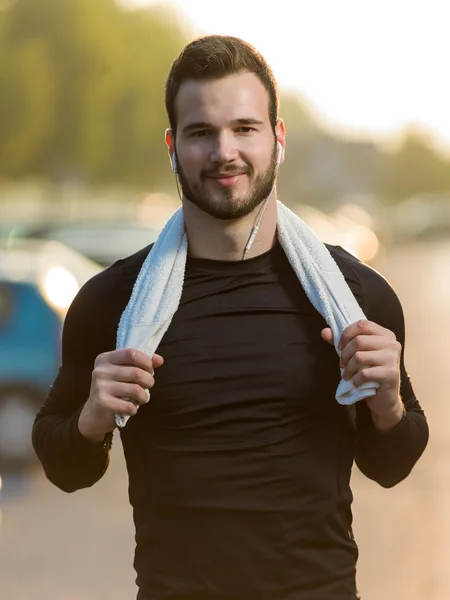 Handsome sporty man  with towel, tired runner resting after even