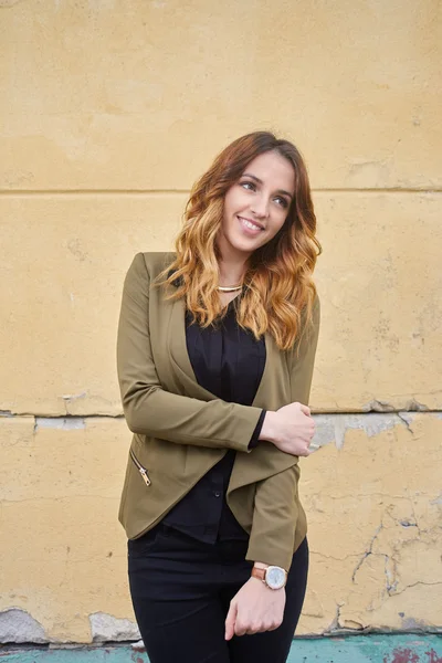 Beautiful business woman standing in front of a yellow wall