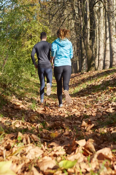 Young running couple jogging in autumn nature