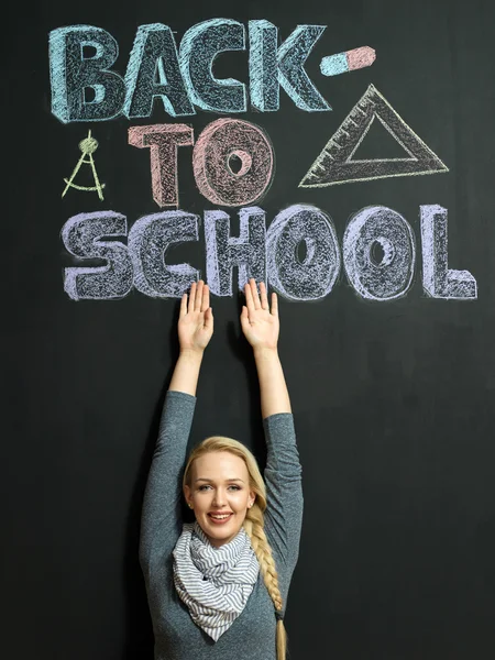 Woman writing 'back to school' on a chalkboard