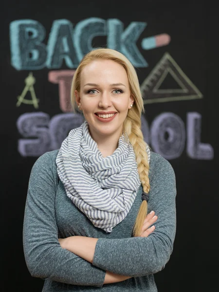 Portrait of a young woman, teacher in front of a blackboard