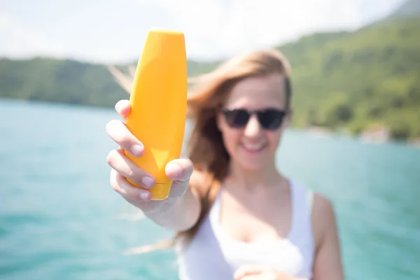 Sunscreen woman applying suntan lotion showing bottle. Beautiful