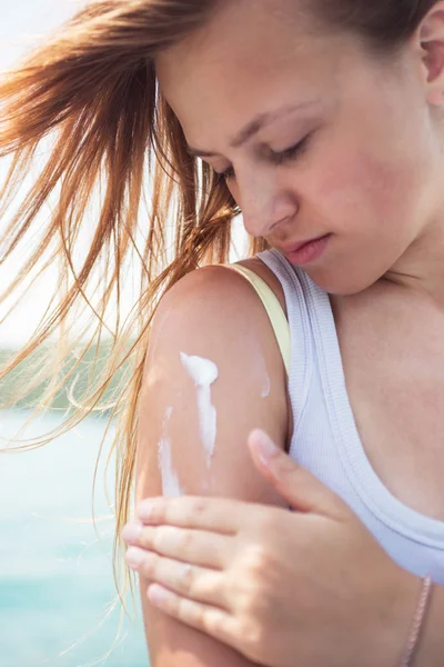 Sunscreen woman applying suntan lotion showing bottle. Beautiful