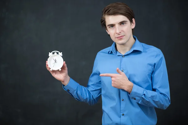 Time. man is looking  at clock with chalk board behind him