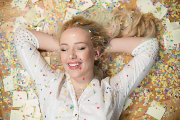 Cheerful young woman is stretching out her hands while confetti