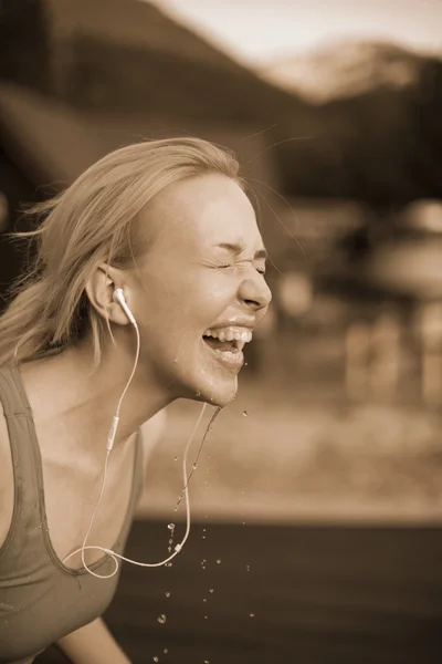 Woman fitness runner drinking and splashing water in her face. F