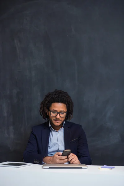 Portrait of happy smart black businessman sitting at desk in off