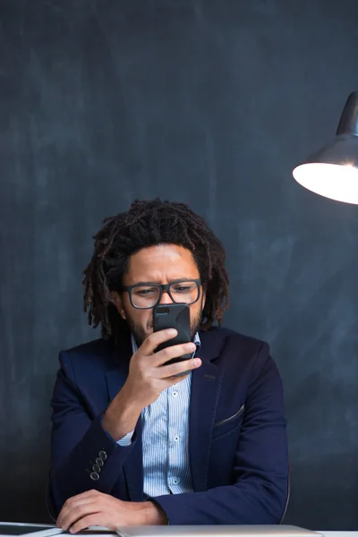 Portrait of happy smart black businessman sitting at desk in off