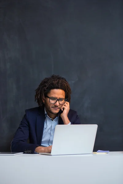 Portrait of happy smart black businessman sitting at desk in off