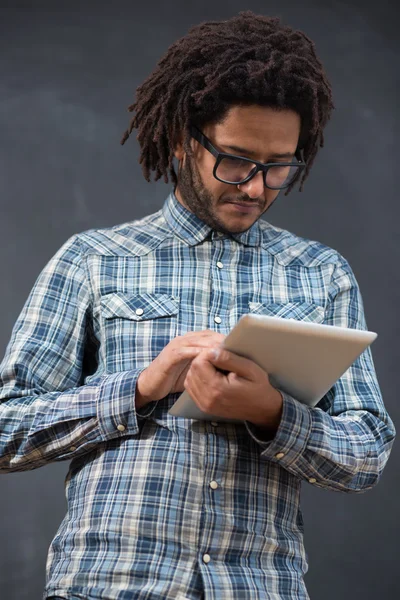 Enjoying his digital tablet. Cheerful young African man holding