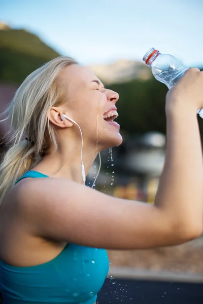 Woman fitness runner drinking and splashing water in her face. F