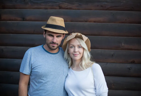 Happy hipster couple hugging and smiling against wooden planks