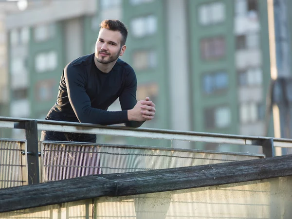 Portrait of Sport and fitness runner man resting on bridge after