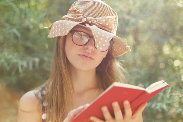 Beautiful country girl reading a book in nature, enjoying sunny