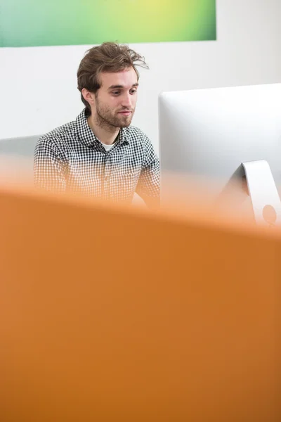 Portrait of young creative with headphone sitting in front of co